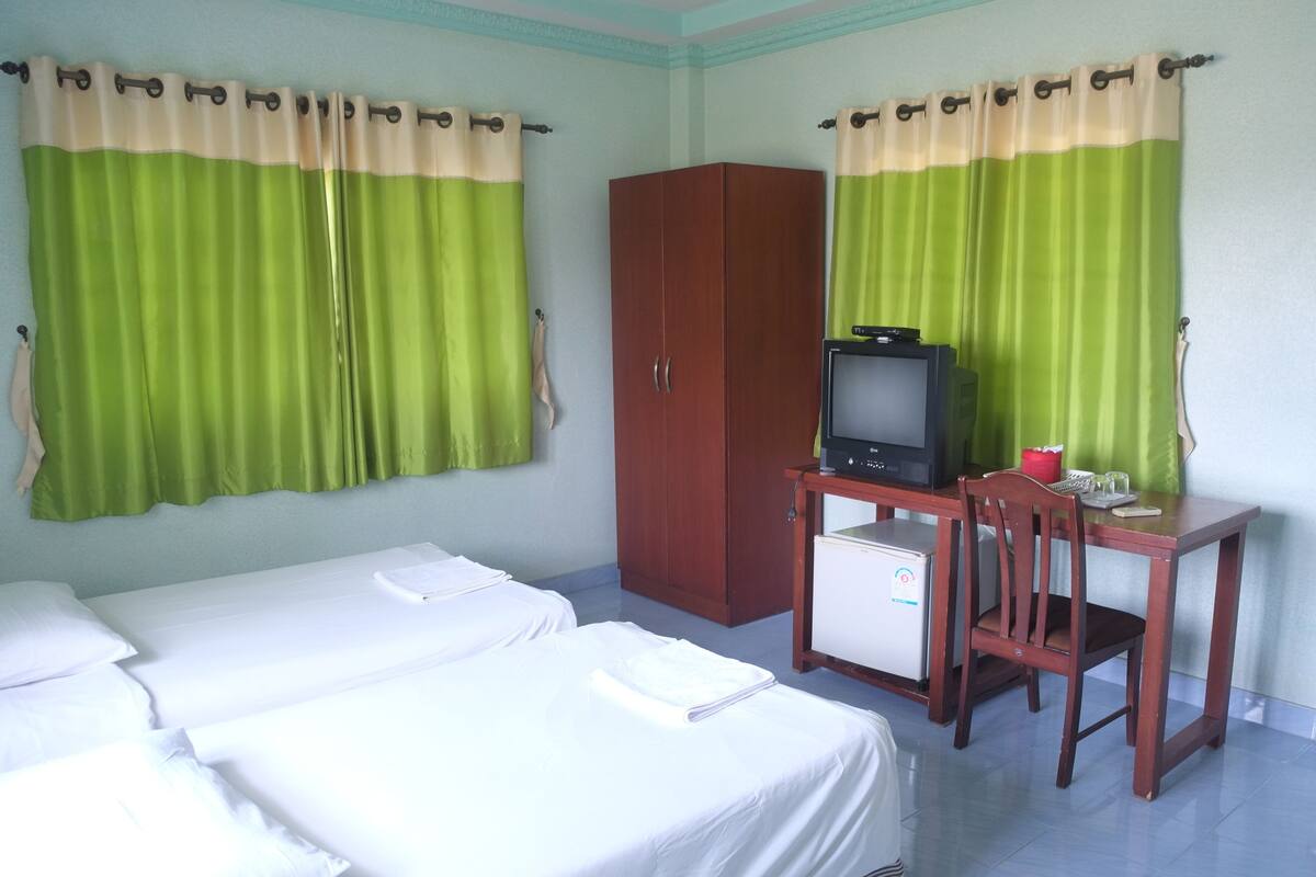 Ein Hotelzimmer mit zwei Betten, einem Schreibtisch mit Fernseher und einem Kleiderschrank.