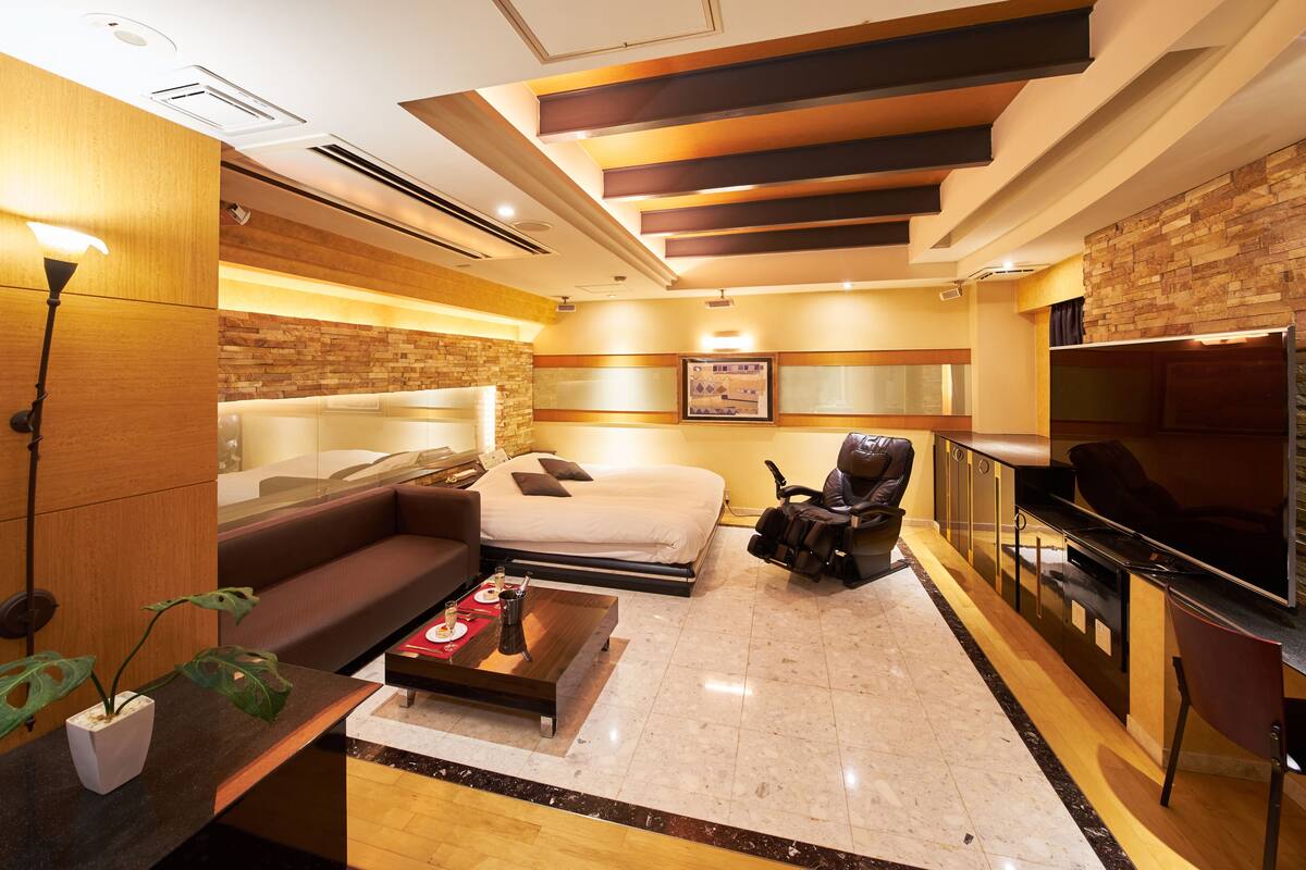 Ein modernes Hotelzimmer mit Bett, Sofa, Couchtisch, Fernseher und Kamin.