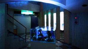 A modern hotel lobby with a glass fish tank, a staircase, and a red emergency exit sign. - Hotel AQUA Blue Yokosuka - Adults Only (Yokosuka)