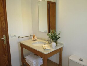 Une salle de bain avec un meuble-lavabo en bois, un évier, un miroir, des toilettes et un porte-serviettes.
