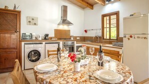 A kitchen with a round table set for dining, a washing machine, a stove, and a refrigerator.