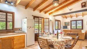 A spacious kitchen with wooden cabinets, a dining area with a table set for four, and a living area with a sofa and TV.
