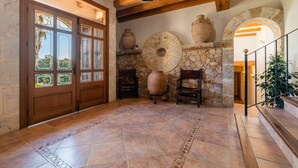 Une pièce spacieuse avec une grande porte en bois, un mur en pierre et une cheminée en pierre surmontée de grands pots.
