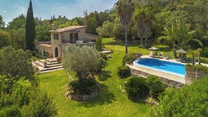 Une villa en pierre dotée d’une piscine, entourée d’une végétation luxuriante et offrant une vue sur la mer.