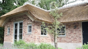 A brick building with a thatched roof and a small tree in front. - Vlindervallei Studio 2p (Ermelo)