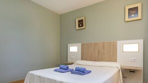 Une chambre d’hôtel comprenant un lit, deux tables de chevet, une tête de lit en bois et deux lampes fixées au mur.