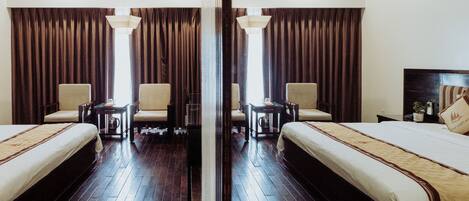 Habitación de hotel con dos camas, un espejo grande, suelo de madera y vistas al exterior.