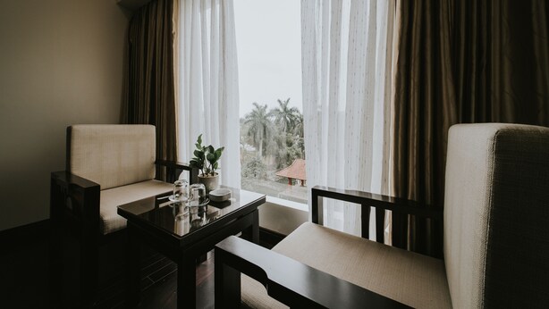 A room with two chairs, a small table, and a window with curtains.