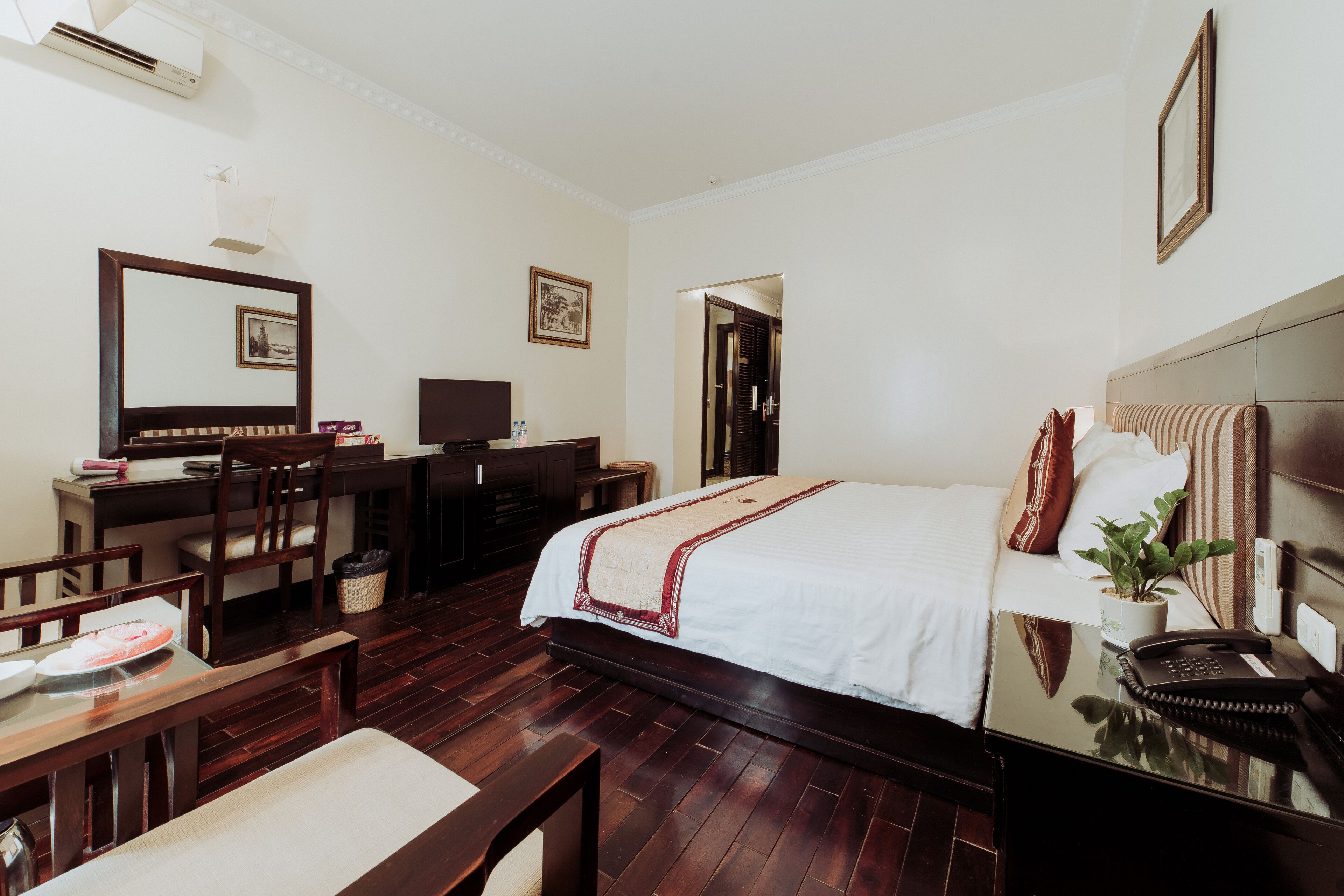 A hotel room with a bed, desk, chair, and a small table.