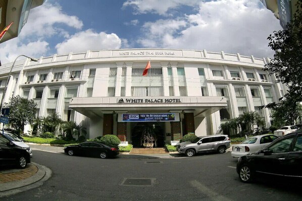 El exterior del hotel White Palace Thai Binh, con una entrada destacada y una bandera.
