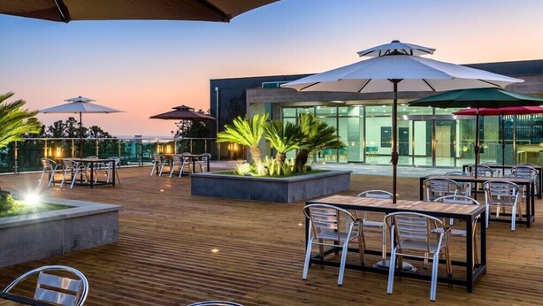 Une terrasse extérieure dotée d’un plancher en bois, de tables, de chaises et de parasols.