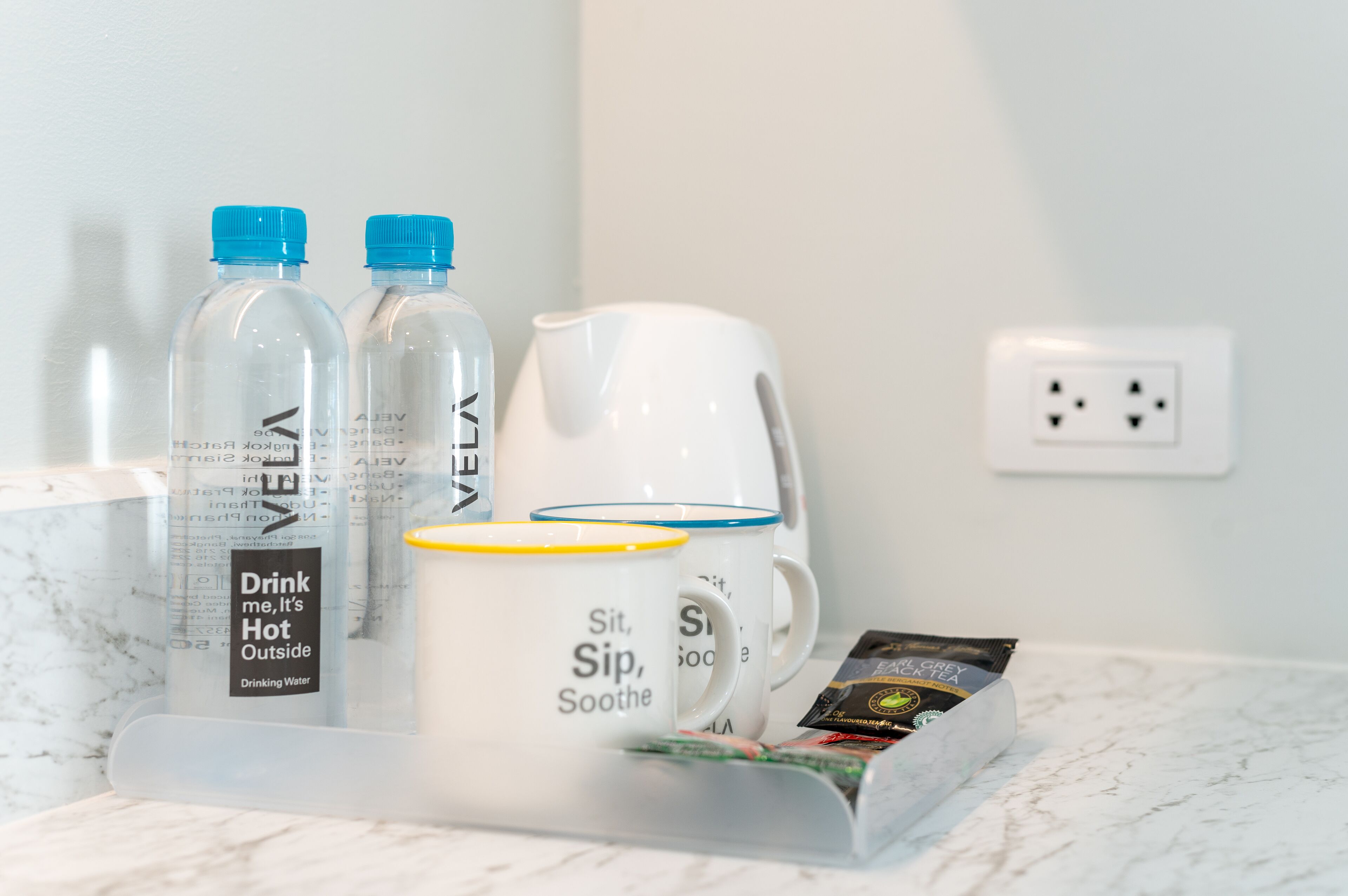 Una encimera de baño con una botella de agua, una taza y un paquete de café.