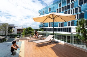 Una piscina al aire libre, sombrillas, sillones reclinables de piscina