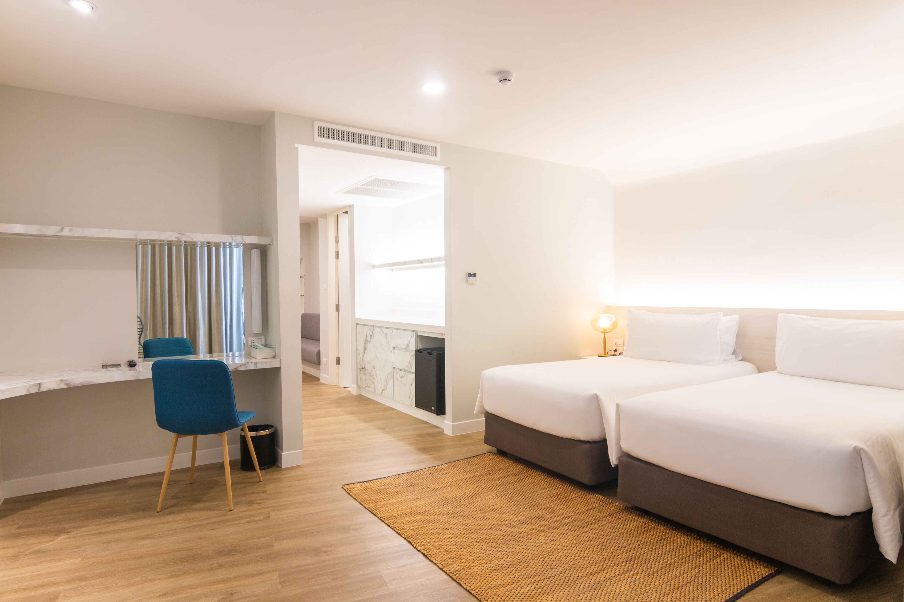 Una habitación de hotel moderna con dos camas, un escritorio y una silla.
