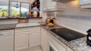 Een moderne keuken met witte kasten, een ingebouwde oven, een granieten werkblad en een raam met uitzicht op de omgeving.
