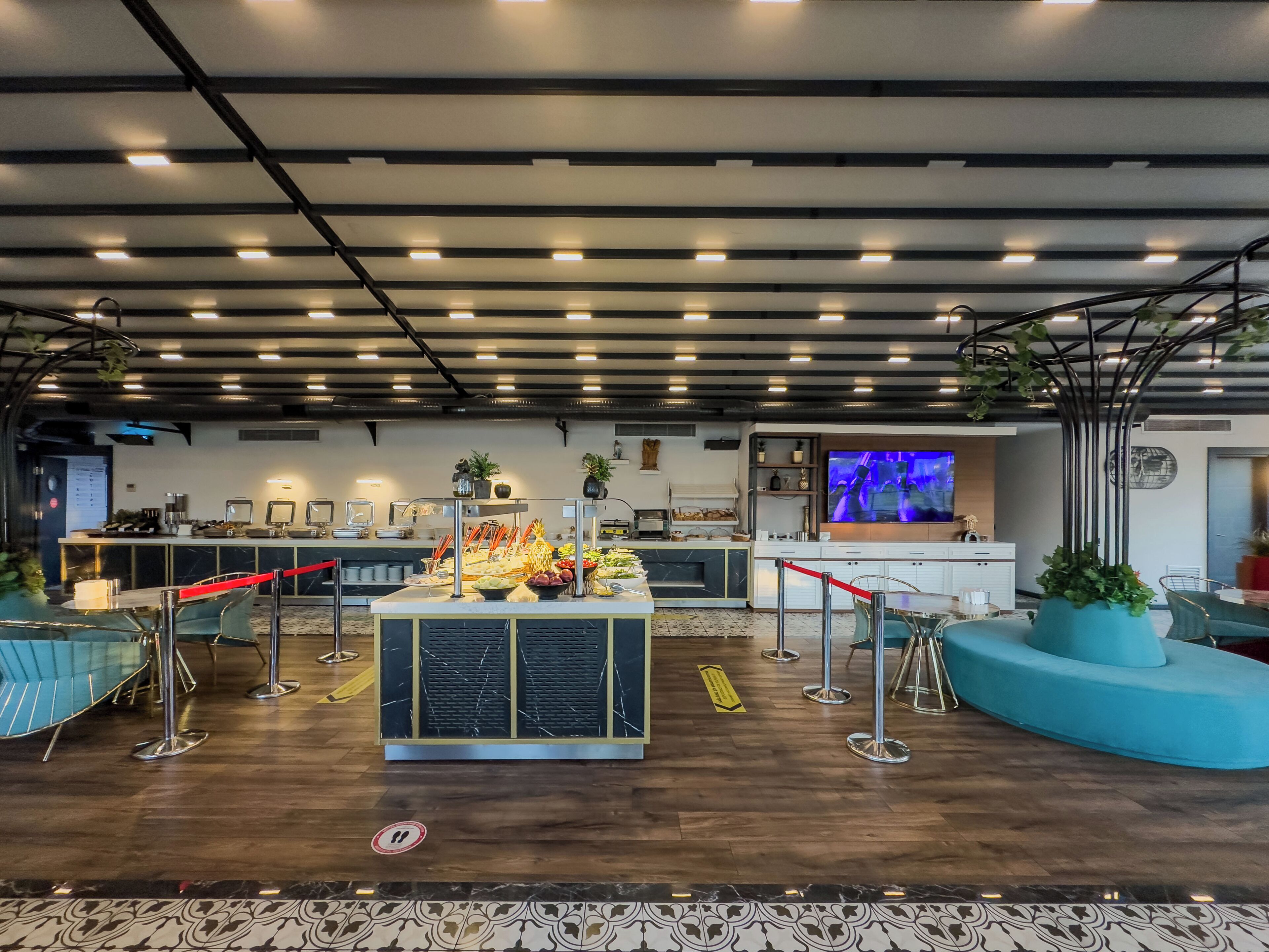 A modern lounge area with a buffet, seating, and a TV screen.
