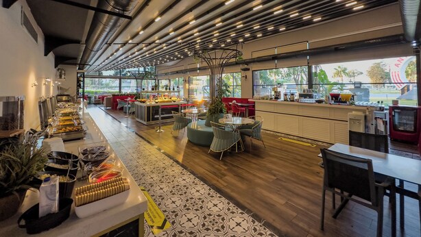 A modern restaurant with a long counter, various food stations, and seating areas. - Leaf Port Hotel (Konyaalti)