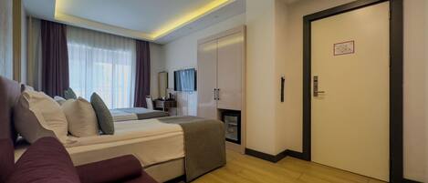 A modern hotel room with a large bed, a sofa, a desk, and a television.