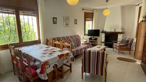 Ein gemütliches Wohnzimmer mit einer Sofagarnitur, einem Esstisch mit Stühlen, einem Fernseher und einem Kamin.