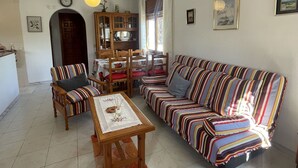 Ein Wohnzimmer mit einem gestreiften Sofa, einem Holztisch und einem Essbereich mit Schrank und Stühlen.