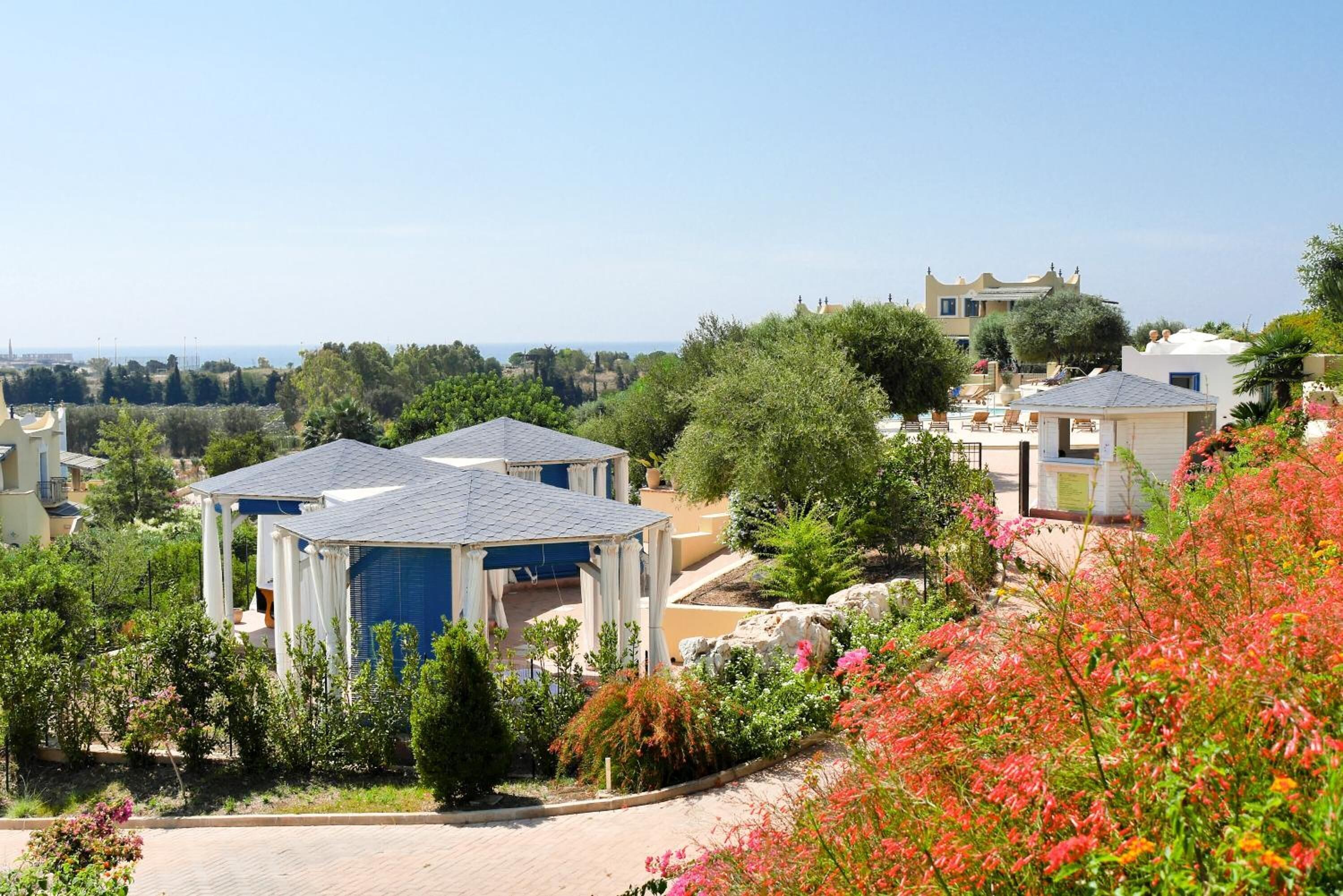 A residential area with houses, a gazebo, and a view of the sea.