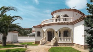 A white building with a curved facade, a balcony with balustrades, and a stone staircase leading to the entrance.