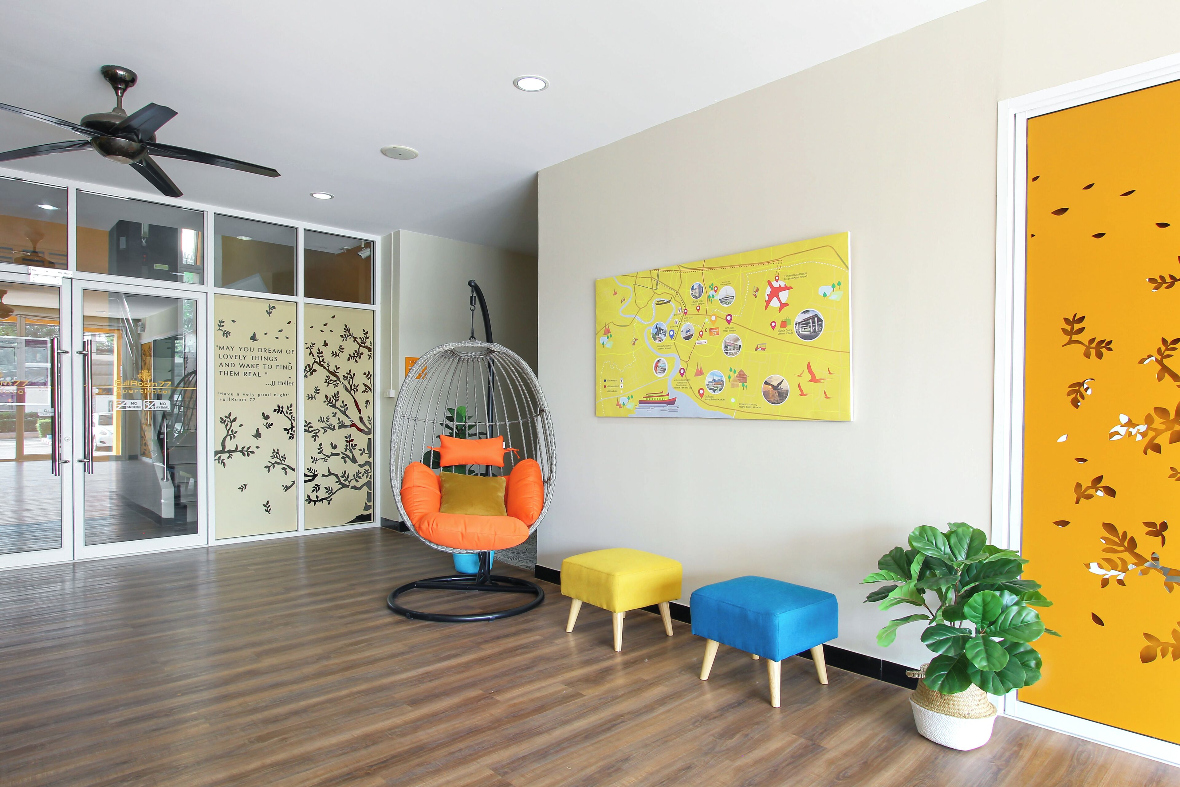 A modern room with a ceiling fan, a hanging chair, two ottomans, and a potted plant.