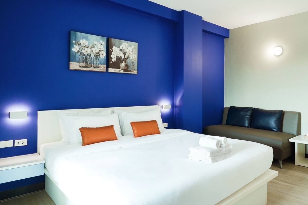 Ein modernes Hotelzimmer mit einem großen Bett, einer Couch und einem kleinen Tisch mit Annehmlichkeiten.