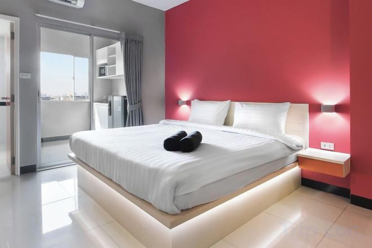 Een moderne hotelkamer met een groot bed, een nachtkastje en uitzicht door een geopende deur.