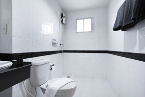 Ein Badezimmer mit weißen Fliesen, einer schwarzen Arbeitsplatte, einer Toilette, einem Fenster und einem Handtuchhalter.