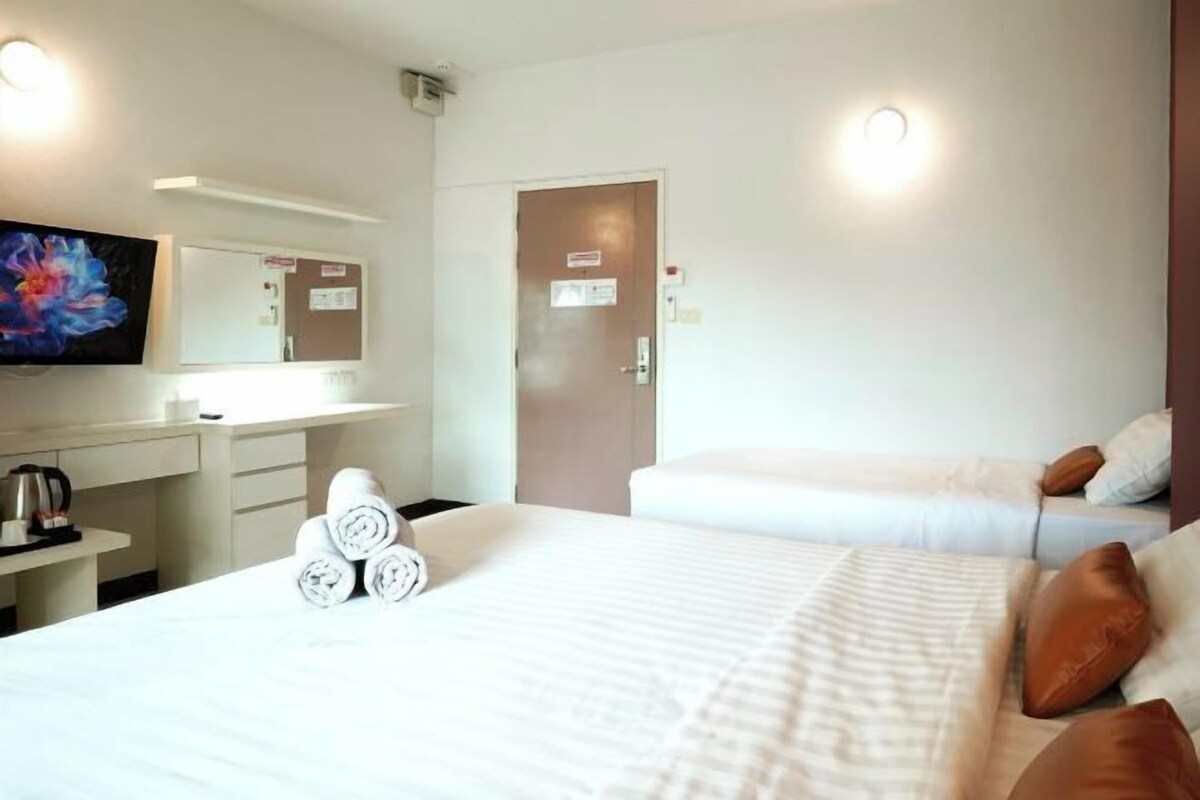 Une chambre d’hôtel avec un lit, un bureau, une chaise, une télévision et une porte.