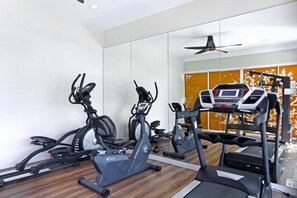 Una palestra con diverse macchine per esercizi, un tapis roulant e uno specchio lungo la parete.