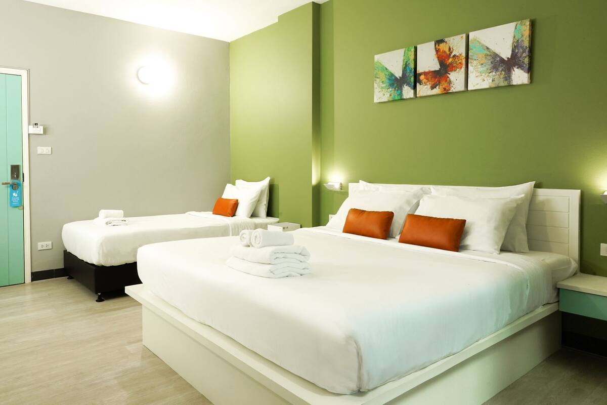 Ein Hotelzimmer mit zwei Betten, grünen Wänden und einem Bild über den Betten.