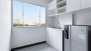 Una cocina moderna con armarios blancos, un refrigerador de acero inoxidable y una ventana con vista a la ciudad.