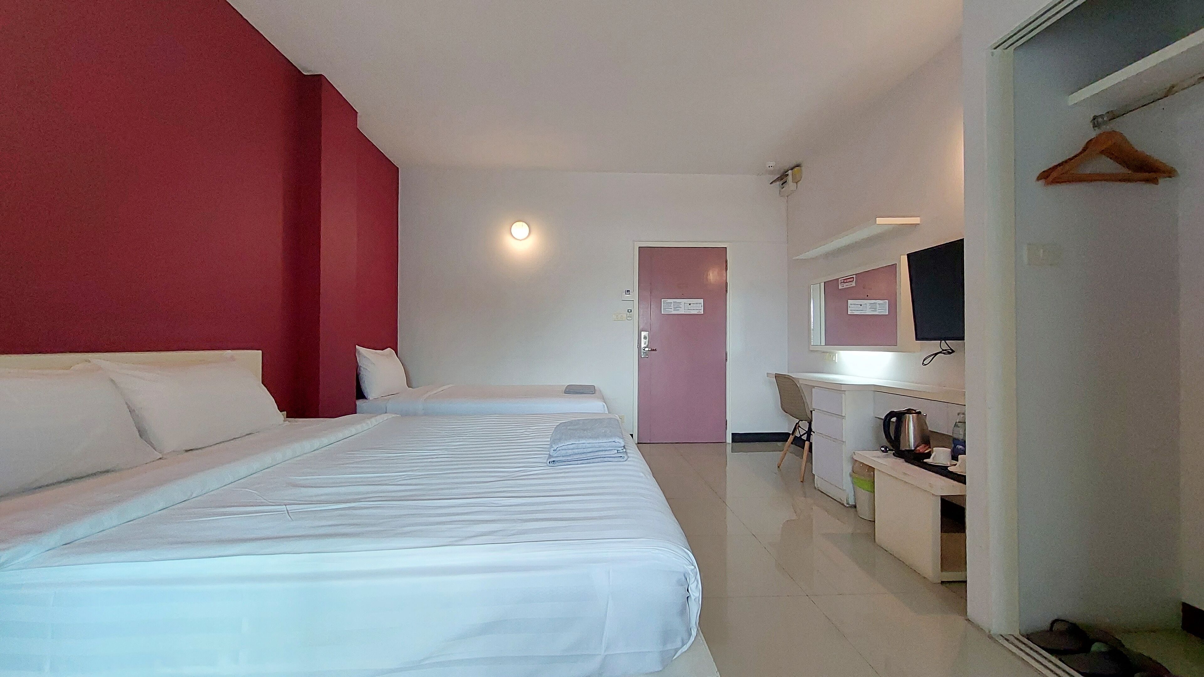 Una habitación de hotel con dos camas, un escritorio, una silla, un televisor y una puerta.