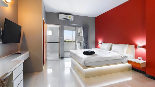 Un dormitorio moderno con cama, mesitas de noche, televisor y vistas al exterior.