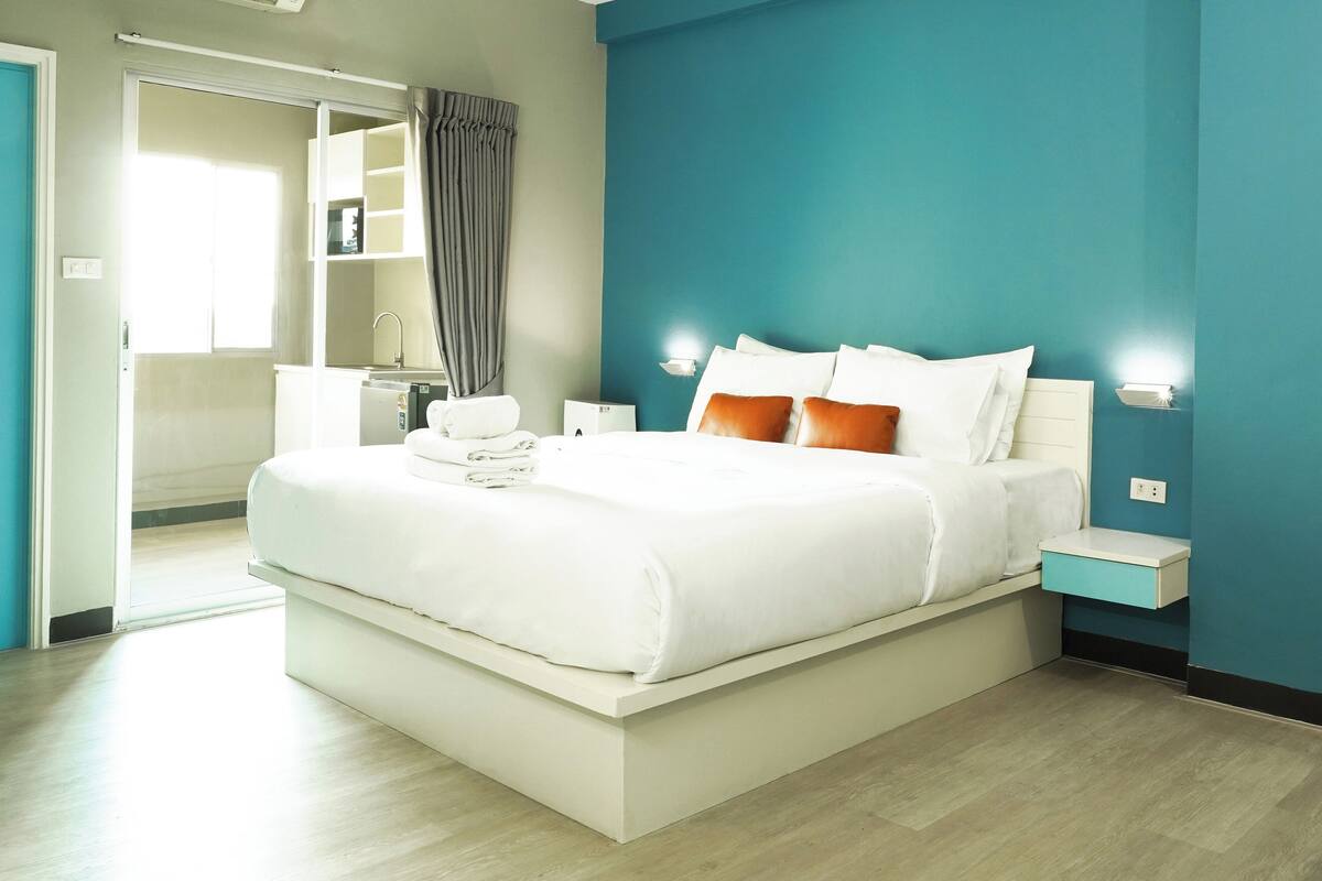 Ein modernes Hotelzimmer mit einem großen Bett, einem Nachttisch, einem Schreibtisch und einem durchgegangene Tür sichtbaren Badezimmer.