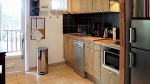 Une cuisine avec des meubles de rangement en bois, un lave-vaisselle, une machine à café et un réfrigérateur.