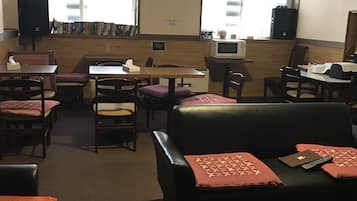 Uma biblioteca com estantes, mesas, cadeiras, um sofá e um micro-ondas numa prateleira.