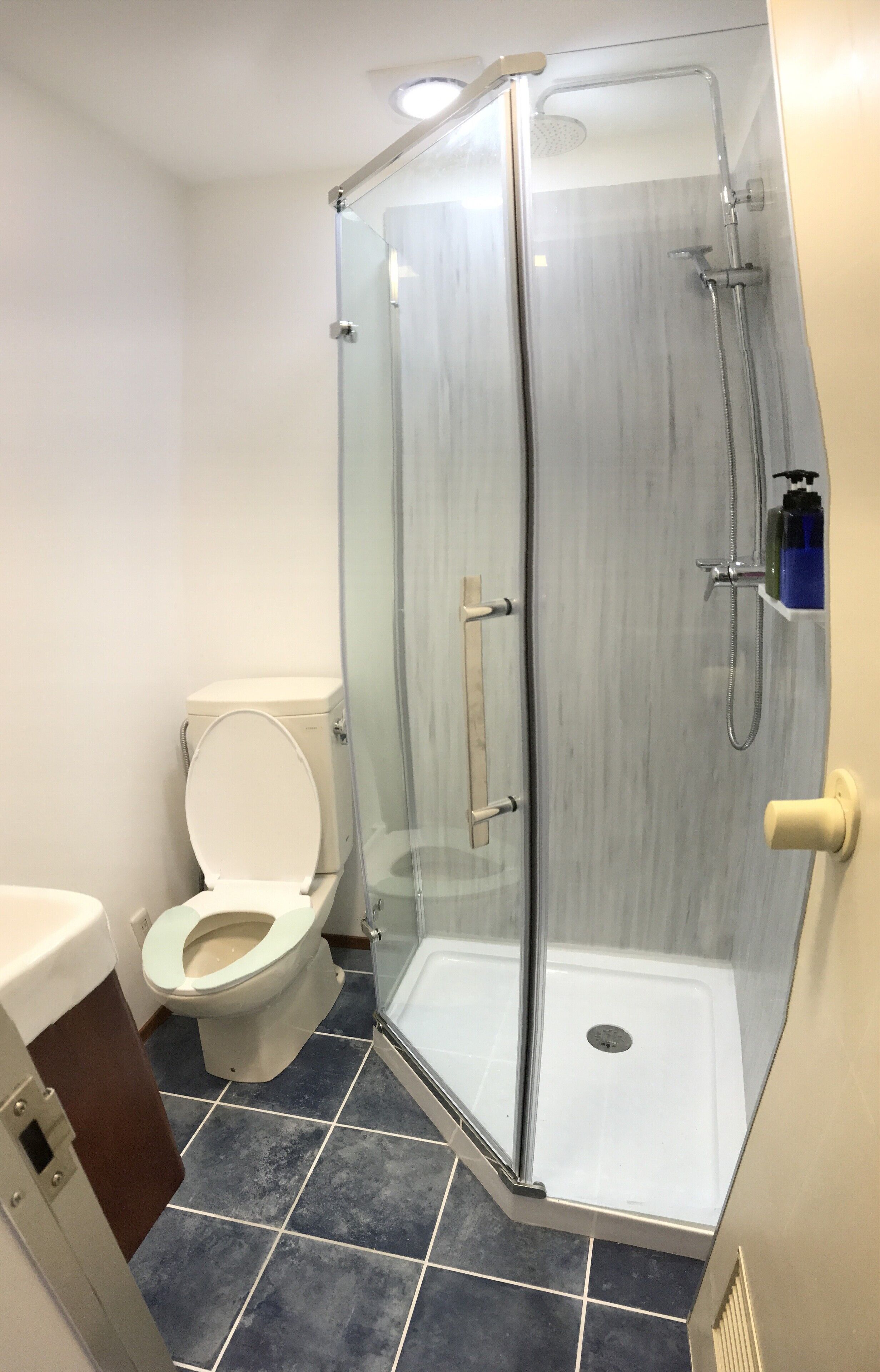 A bathroom with a glass-enclosed shower, a toilet, and a sink.