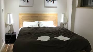 A bedroom with a wooden bed, two bedside tables with lamps, and two abstract paintings on the wall.