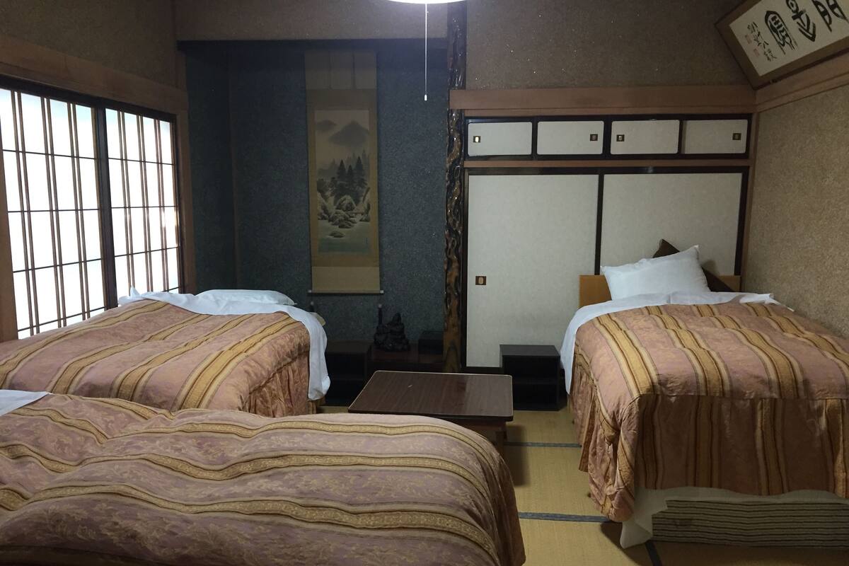 Une pièce de style japonais traditionnel, avec deux lits, un sol recouvert de tatamis, un paravent shoji et un futon.