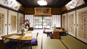 A traditional Japanese room with tatami flooring, low tables, and purple cushions. - Kanau (Gojo)