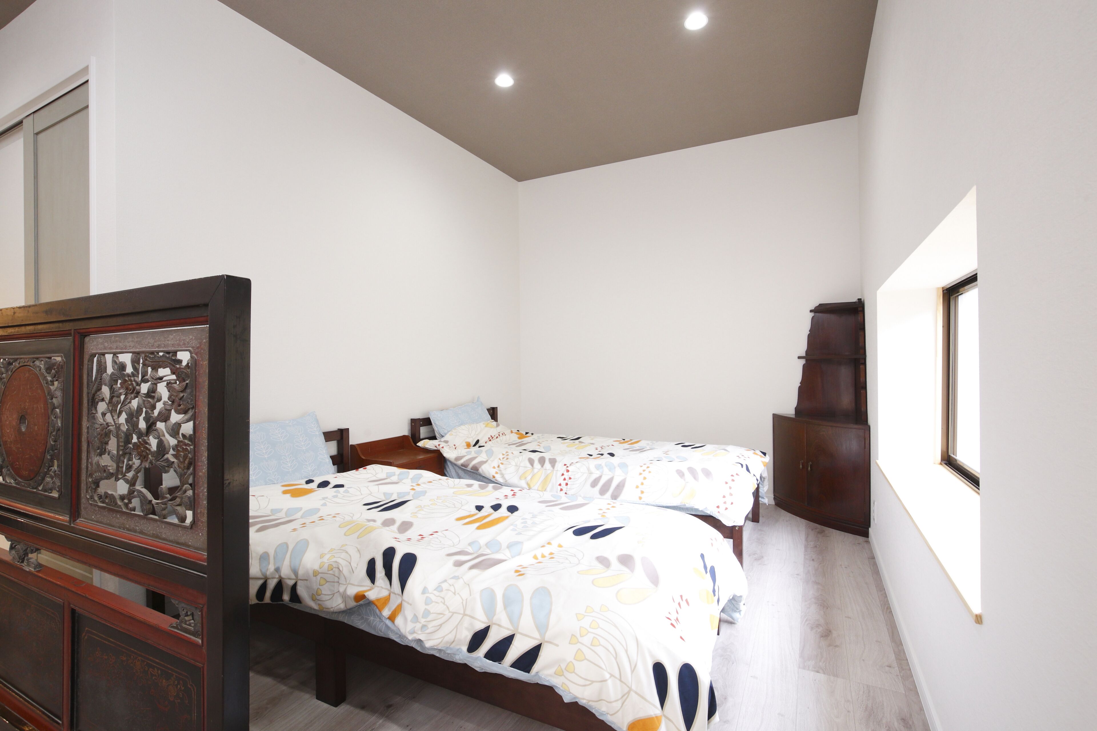 A bedroom with two beds, a wooden headboard, and a cabinet.