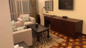 A living room with a sofa, a coffee table, a TV, and a cabinet. - Desalegn Hotels Lodge And Apartment (Addis Ababa)