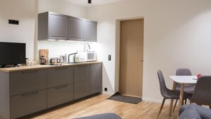 A modern kitchen with grey cabinets, a microwave, and a coffee maker. There is a dining area with a table and chairs. - City heart Ülikooli Tartu Home Apts. (Tartu)