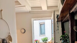 A modern kitchen with a wooden countertop, a black chair, and a black bench. There is a clock on the wall and a door leading to an outdoor patio with a wooden deck and potted plants. - Apartment in historischem Gebäude (Uelzen)