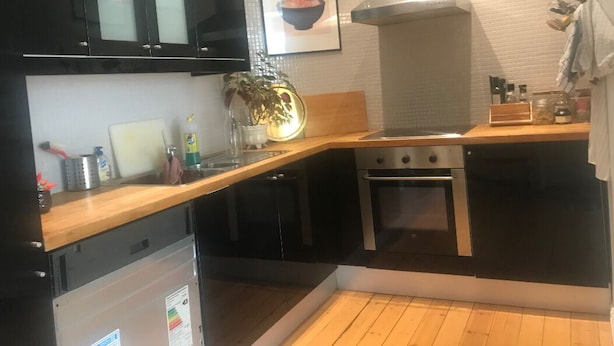 A modern kitchen with black cabinets, a stainless steel stove, and a wooden countertop. - StayPlus Apartment near Vigeland Park (Oslo)
