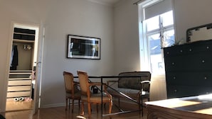 A spacious living room with a high ceiling, a dining area with chairs, a black dresser, and a large window providing natural light. - StayPlus Apartment near Vigeland Park (Oslo)