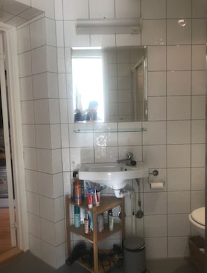 A bathroom with a white sink, mirror, and tiled walls. - StayPlus Apartment near Vigeland Park (Oslo)